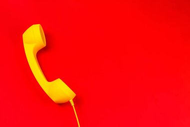 Kırmızı arka planda sarı bir cep telefonu. Boşluğu kopyala.