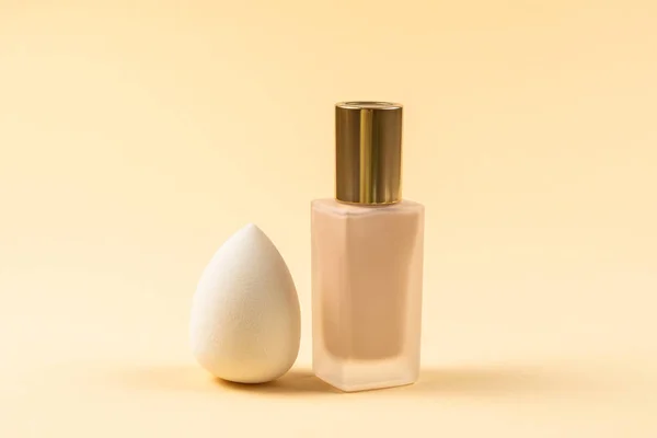 Small, medium and large  white beauty blender and makeup foundation on beige background. Top view.