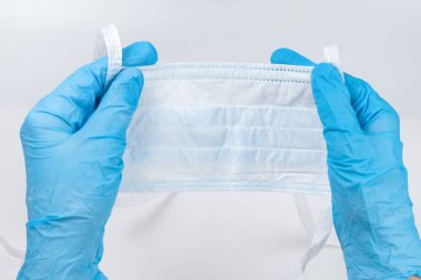 Kadın koruyucu maske takıyor ve mavi lastik eldiven takıyor. Beyazda izole edilmiş.