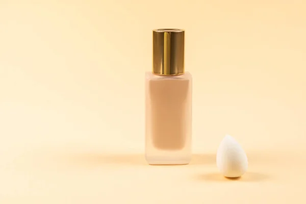 Small, medium and large  white beauty blender and makeup foundation on beige background. Top view.