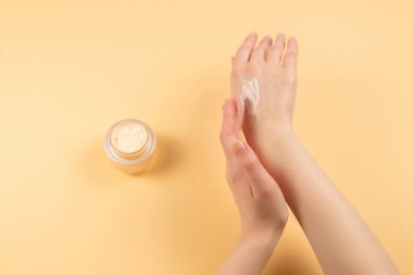 El kremi ve kadın eli bej arka planda. Boşluğu kopyala. 