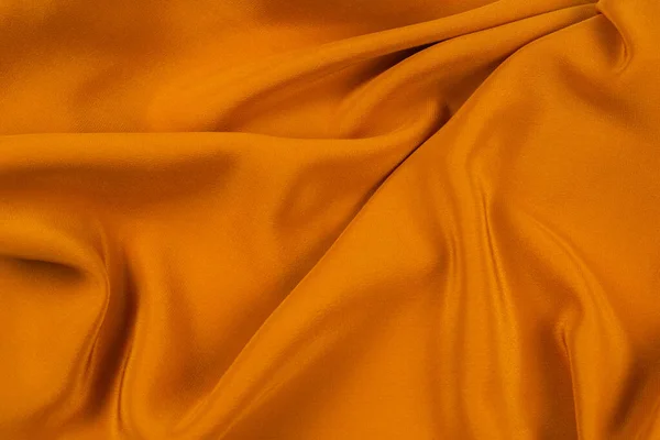 Golden silk or satin luxury fabric texture can use as abstract background. Top view.