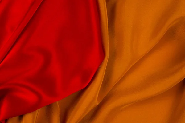 Red and orange silk or satin luxury fabric texture can use as abstract background. Top view.