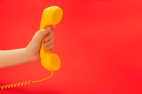 女性の手に赤い背景に黄色の携帯電話 スペースのコピー — ストック写真
