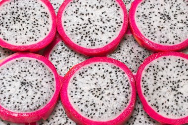 Tatlı ejderha meyvesi ya da pitaya dilimleri arka planda.