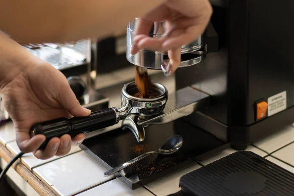 Barista grinding fresh coffee bean into portafilter for espresso — Stock Photo, Image
