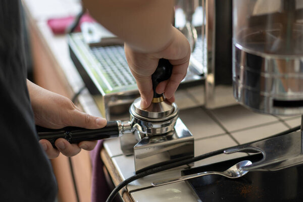 Barista tamped ground coffee in a portafilter