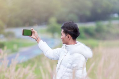 Erkek model çayır on beyaz kazak giyiyor. Selfie.