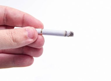 Bir adam yanan sigarayı beyazın üzerinde tutuyor.