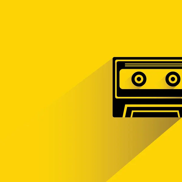 黄色の背景に影付きカセットテープ — ストックベクタ
