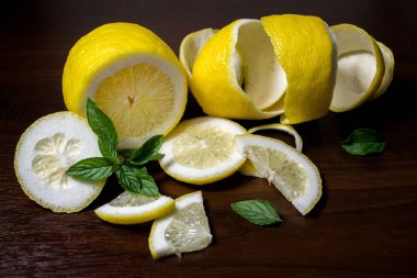 Limon kabuğu veya koyu kahverengi ahşap arka plan ile güzel kokulu, yeşil nane fışkın limon twist. Limon dilimleri üzerinden kesilir. Yakın çekim. Narenciye limon. Mentha.