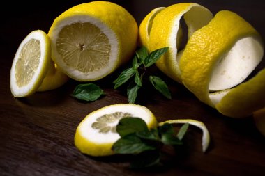 Limon kabuğu veya koyu kahverengi ahşap arka plan ile güzel kokulu, yeşil nane fışkın limon twist. Limon dilimleri üzerinden kesilir. Yakın çekim. Narenciye limon. Mentha.