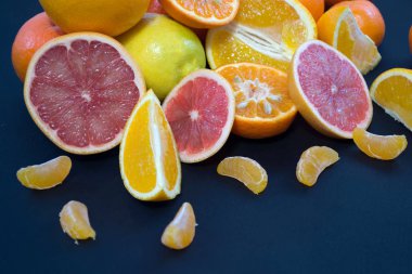 Koyu mavi bir arka plan üzerinde renkli narenciye. Limon dilimleri ve kabuğu. Narenciye reticulata. Narenciye sonat. Narenciye limon. Citrus sinensis. 