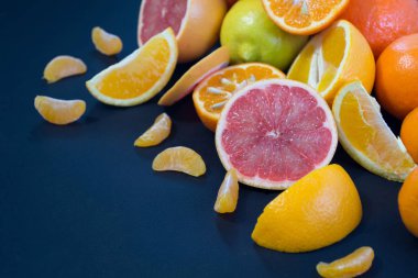 Koyu mavi bir arka plan üzerinde renkli narenciye. Limon dilimleri ve kabuğu. Narenciye reticulata. Narenciye sonat. Narenciye limon. Citrus sinensis. 