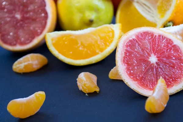 Colored Citrus fruits on a dark blue background. Slices of citrus and peel. Citrus reticulata. Citrus paradisi. Citrus limon. Citrus sinensis.