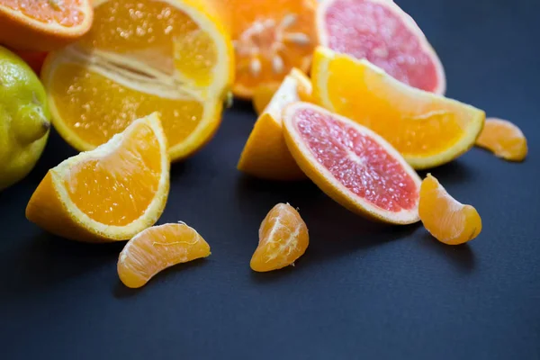 Colored Citrus fruits on a dark blue background. Slices of citrus and peel. Citrus reticulata. Citrus paradisi. Citrus limon. Citrus sinensis.