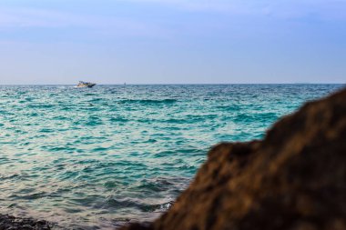 Yeşil Deniz dalgası Sahilde kayalara çarptı ve sürat teknesi yüzüyor