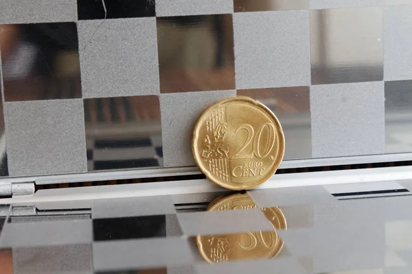 Moeda de euro com uma denominação de 20 cêntimos de euro no espelho refletem carteira, fundo chequered — Fotografia de Stock