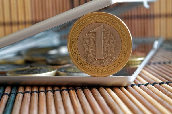 Σωρός από Τουρκικά κέρματα ονομαστικής αξίας 1 Λίρα σε καθρέφτη αντανακλούν πορτοφόλι ψέματα σε ξύλινα μπαμπού πίνακα φόντο — Φωτογραφία Αρχείου