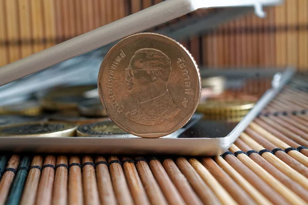 Stapel von Münzen mit einer Vordermünze im Wert von fünf Baht im Spiegel spiegeln Brieftasche liegt auf hölzernem Bambus-Tischhintergrund - Rückseite — Stockfoto