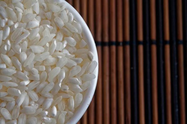 Arroz orgánico en textura de plato pequeño, arroz molido corto asiático sin cocer como fondo. El concepto de una nutrición adecuada y un estilo de vida saludable. Vista superior, primer plano como fondo o textura — Foto de Stock
