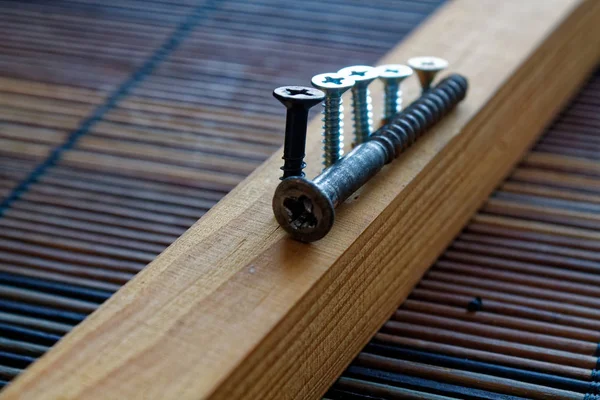 A fából készült deszka csavarva szétszórt csavarok — Stock Fotó