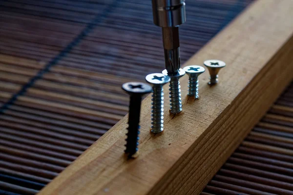Verstreute Schraube mit Schraubenzieher in die Holzplanke geschraubt — Stockfoto