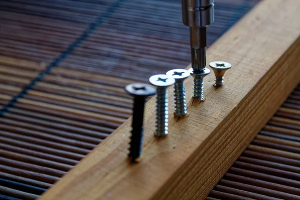 Scattered screw screwed with screwdriver into the wooden plank — Stock Photo, Image