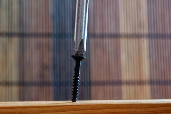 Parafuso parafusado com chave de fenda na prancha de madeira — Fotografia de Stock