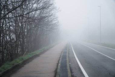 Puslu sisli karanlık gizemli pempty alanları üzerinden giden asfalt yol