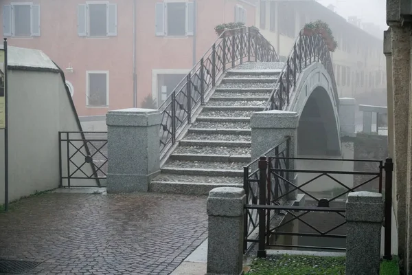 Kanal und Fußgängerbrücke, nebliges Wetter in Italien — Stockfoto