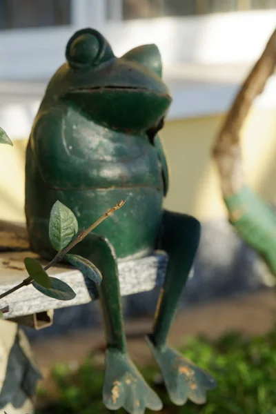 钢绿色青蛙坐在石楼梯上交叉的双腿手势。花园雕像 选择性焦点在青蛙的脸. — 图库照片