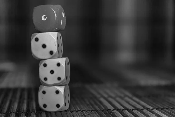 Monochrome Stack of three white plastic dices and one red dice on brown wooden board background. Six sides cube with black dots. Number 1, 3, 4, 5 — Stock Photo, Image