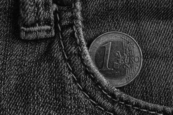 Monochrome Euro coin with a denomination of 1 euro in the pocket of blue denim jeans.