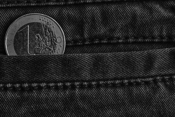 Monochrome Euro coin with a denomination of one euro in the pocket of blue denim jeans