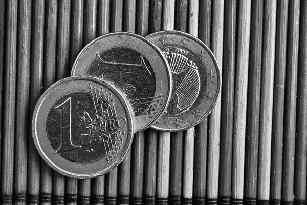 Monocromático Três moedas de euro jazem na mesa de bambu de madeira A denominação é um euro . — Fotografia de Stock