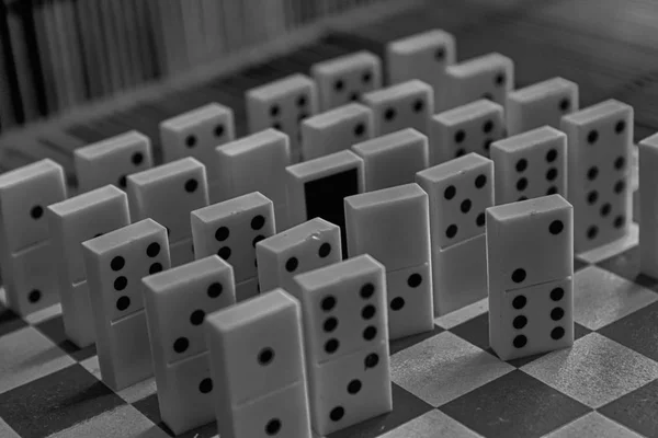 Monocromático peças Domino em uma fileira, lado de trás no fundo de mesa de madeira marrom de bambu . — Fotografia de Stock