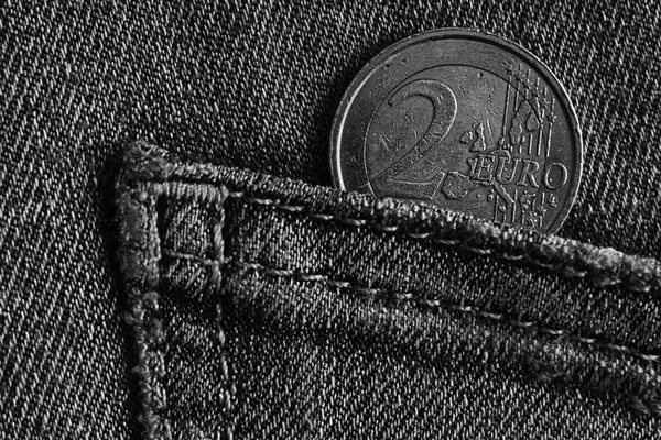 Monochrome Euro coin with a denomination of 1 euro in the pocket of blue denim jeans