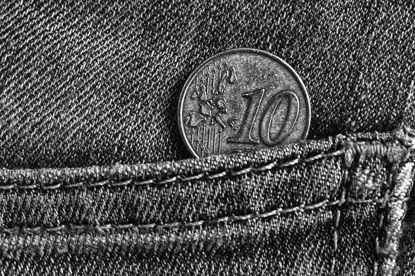 Euro coin with a denomination of 10 euro cents in the pocket of worn denim jeans, monochrome shot