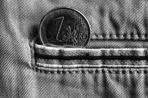 Euro coin with a denomination of 1 euro in the pocket of denim jeans with stripe, monochrome shot