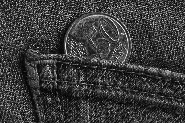 Euro coin with a denomination of 50 euro cents in the pocket of worn denim jeans, monochrome shot — Stock Photo, Image