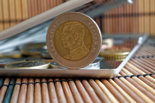 Stapel von Münzen mit einer Vordermünze im Wert von zehn Baht im Spiegel spiegeln Brieftasche liegt auf hölzernem Bambus-Tischhintergrund - Rückseite — Stockfoto
