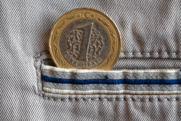 Turkish coin with a denomination of one lira in the pocket of beige denim jeans with blue stripe