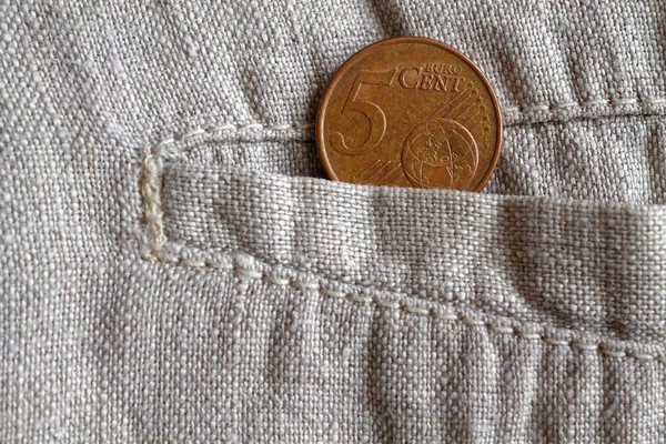 Монета евро номиналом 5 евро в кармане изношенных бельевых брюк — стоковое фото