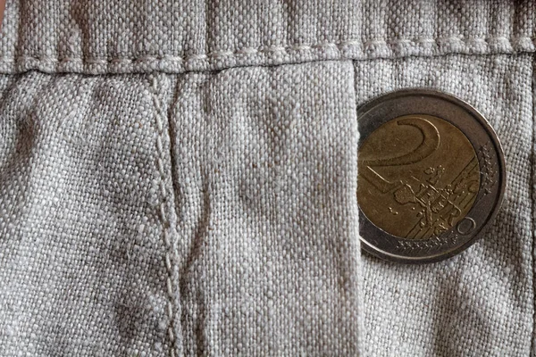 Euro coin with a denomination of 2 euro in the pocket of old linen pants