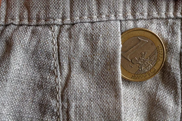 Euro coin with a denomination of one euro in the pocket of old linen pants