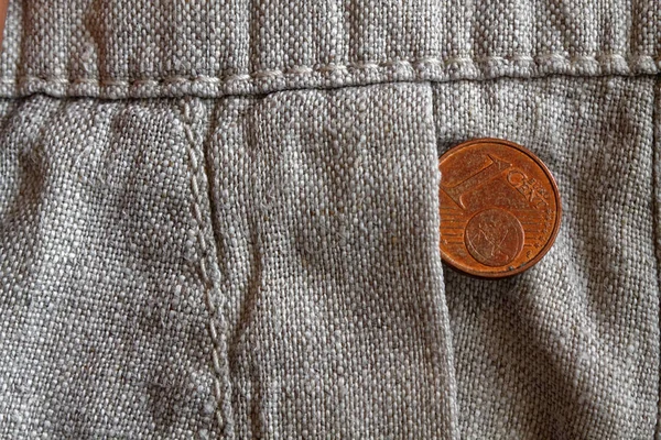 Euro coin with a denomination of 1 euro cent in the pocket of old linen pants