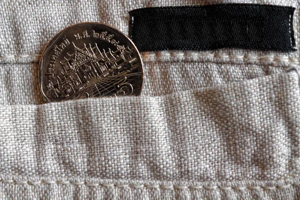 Thai coin with a denomination of 5 baht in the pocket of linen pants with black stripe for label — Stock Photo, Image