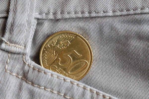 Euro coin with a denomination of fifty euro cents in the pocket of old beige denim jeans — Stock Photo, Image