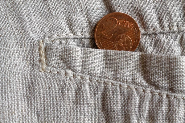 Euro coin with a denomination of 2 euro cents in the pocket of worn linen pants